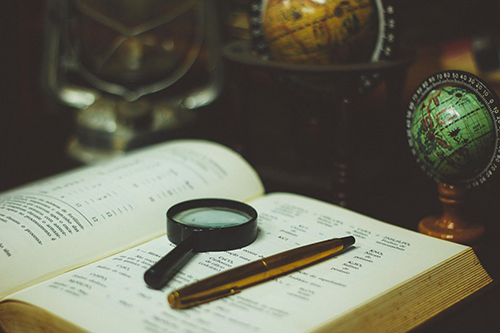 A pen and magnifying glass lying on an open book