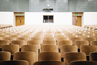 Rows of empty wooden chairs in a large lecture hall