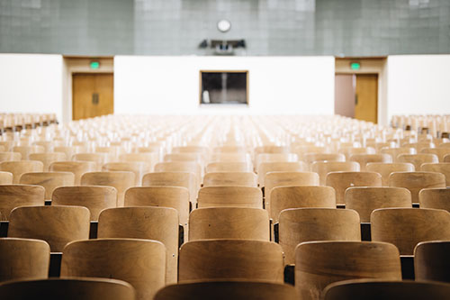 An image showing wooden seats in an empty lecture hall