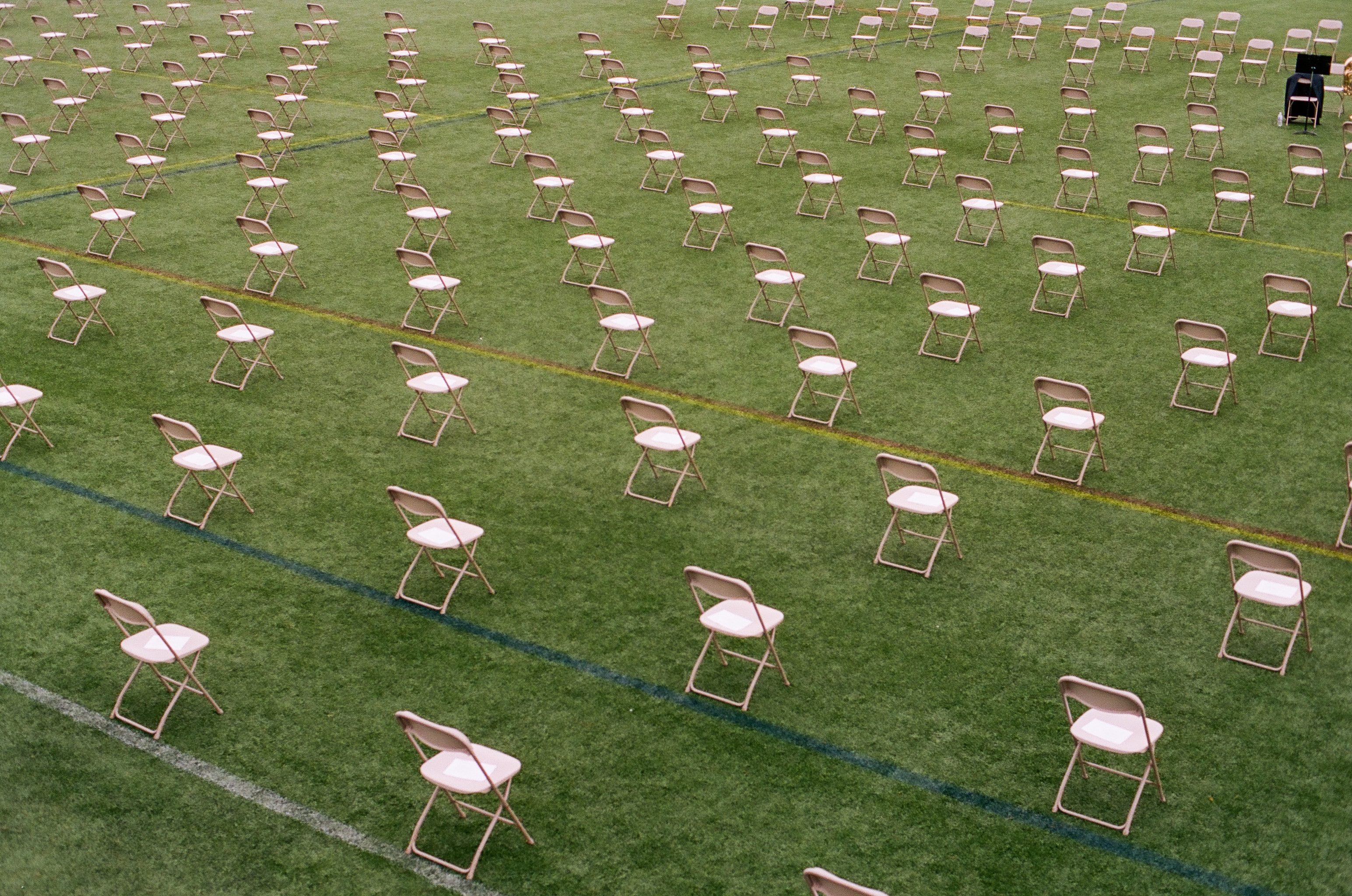 Empty chairs on a large athletic field, each placed six feet apart