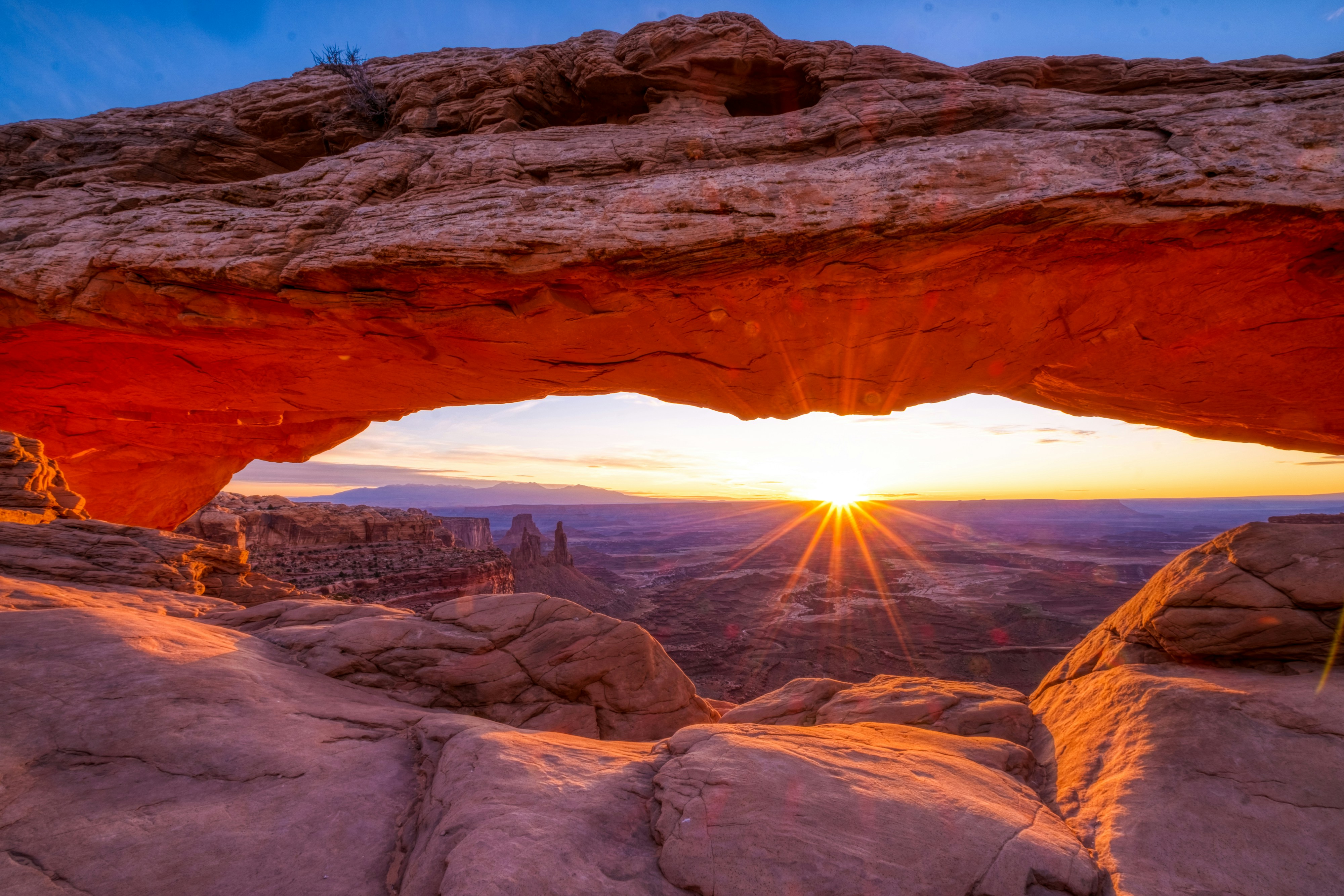 A sunrise seen through an arch in the desert.