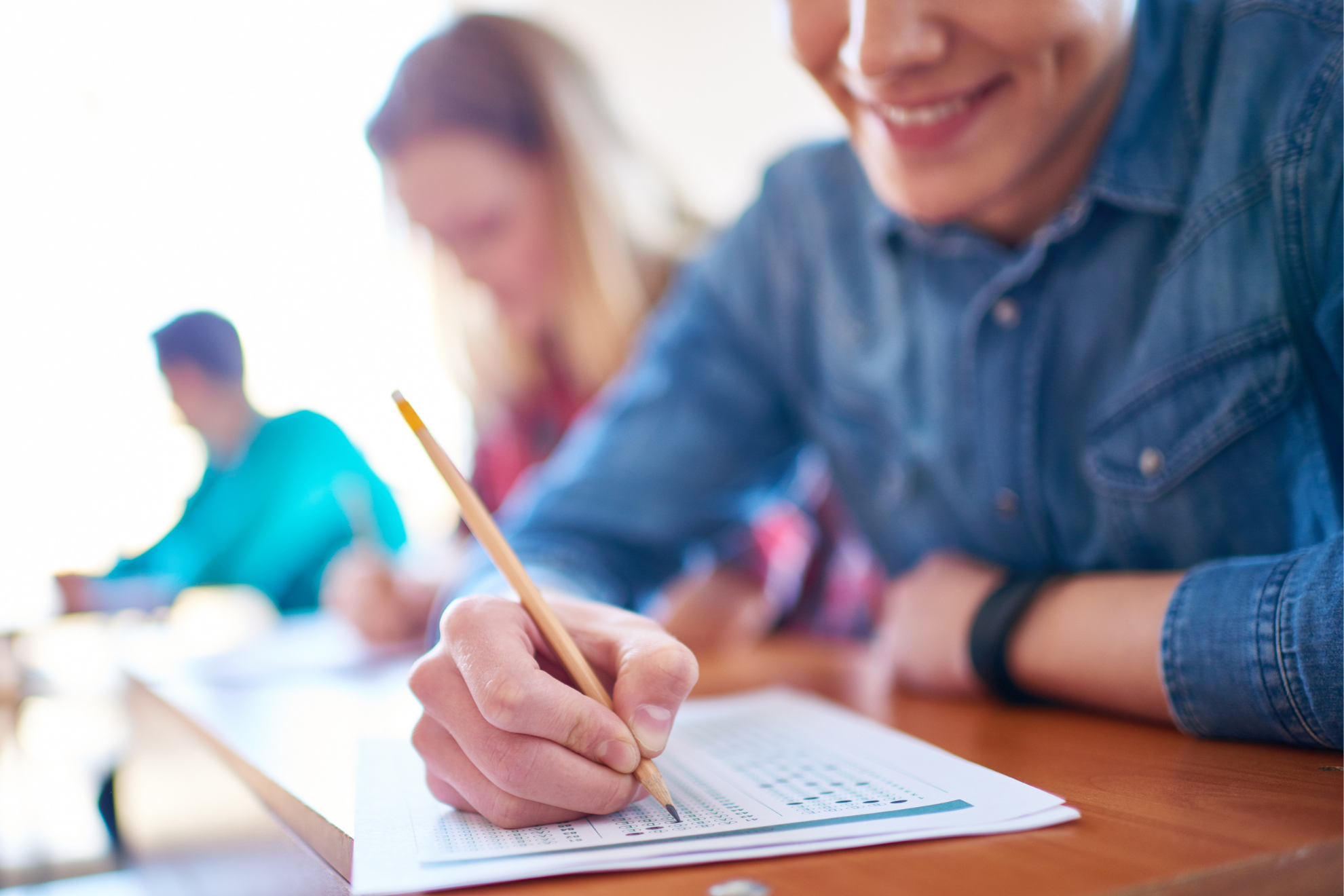 A young man taking an exam in a classroom.