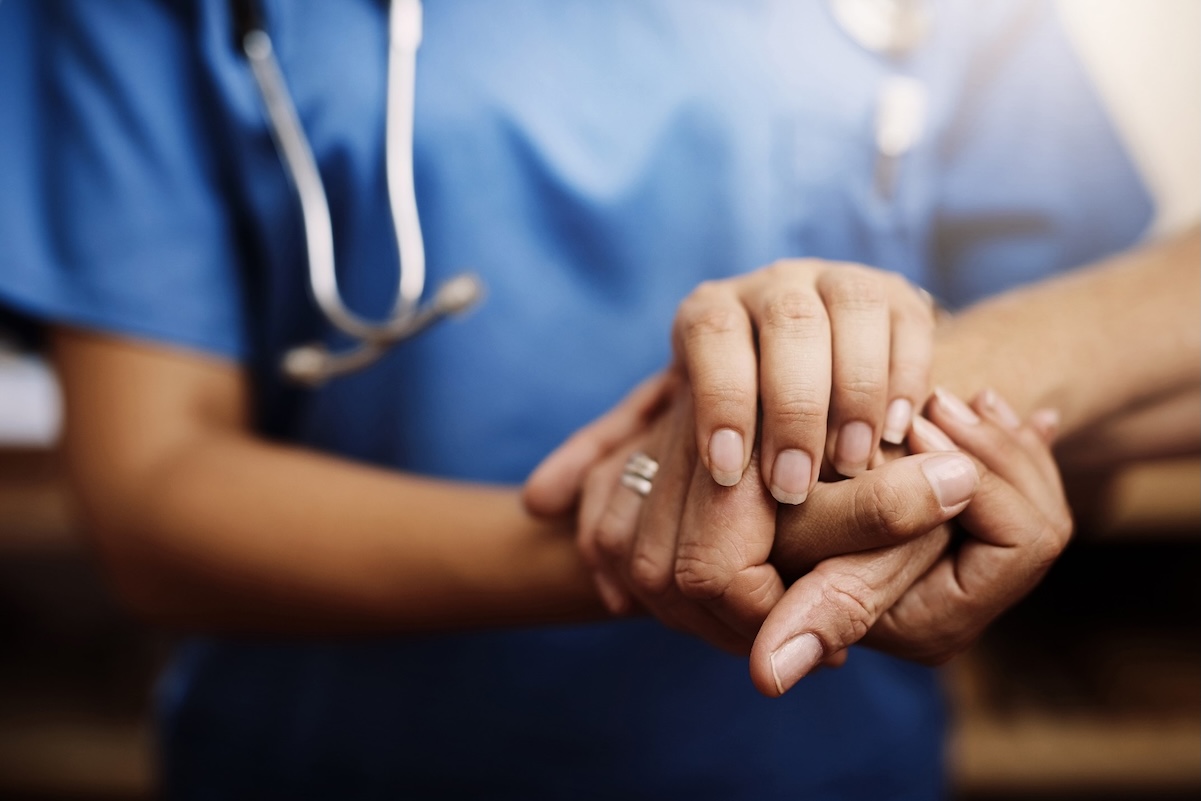 A nurse holding a patient's hand.